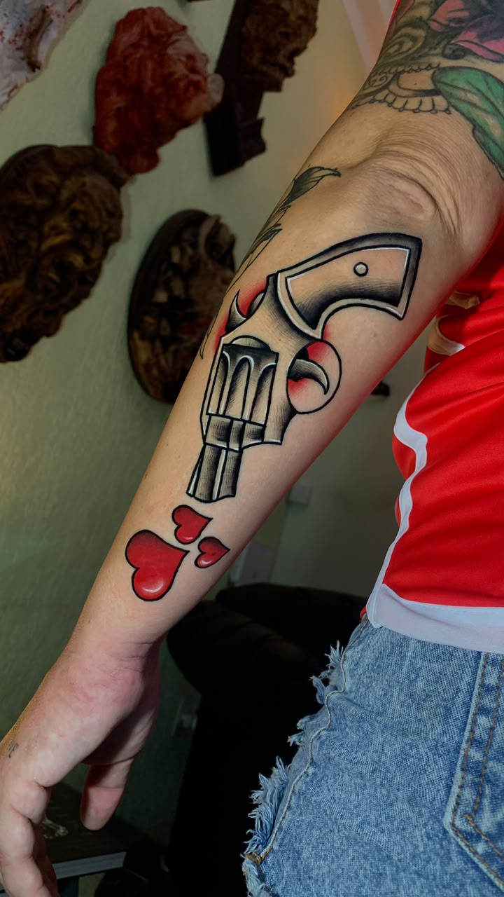 Tatuagem Old School Revólver & Corações na região antebraço feita por Juh Godoy em Porto Alegre