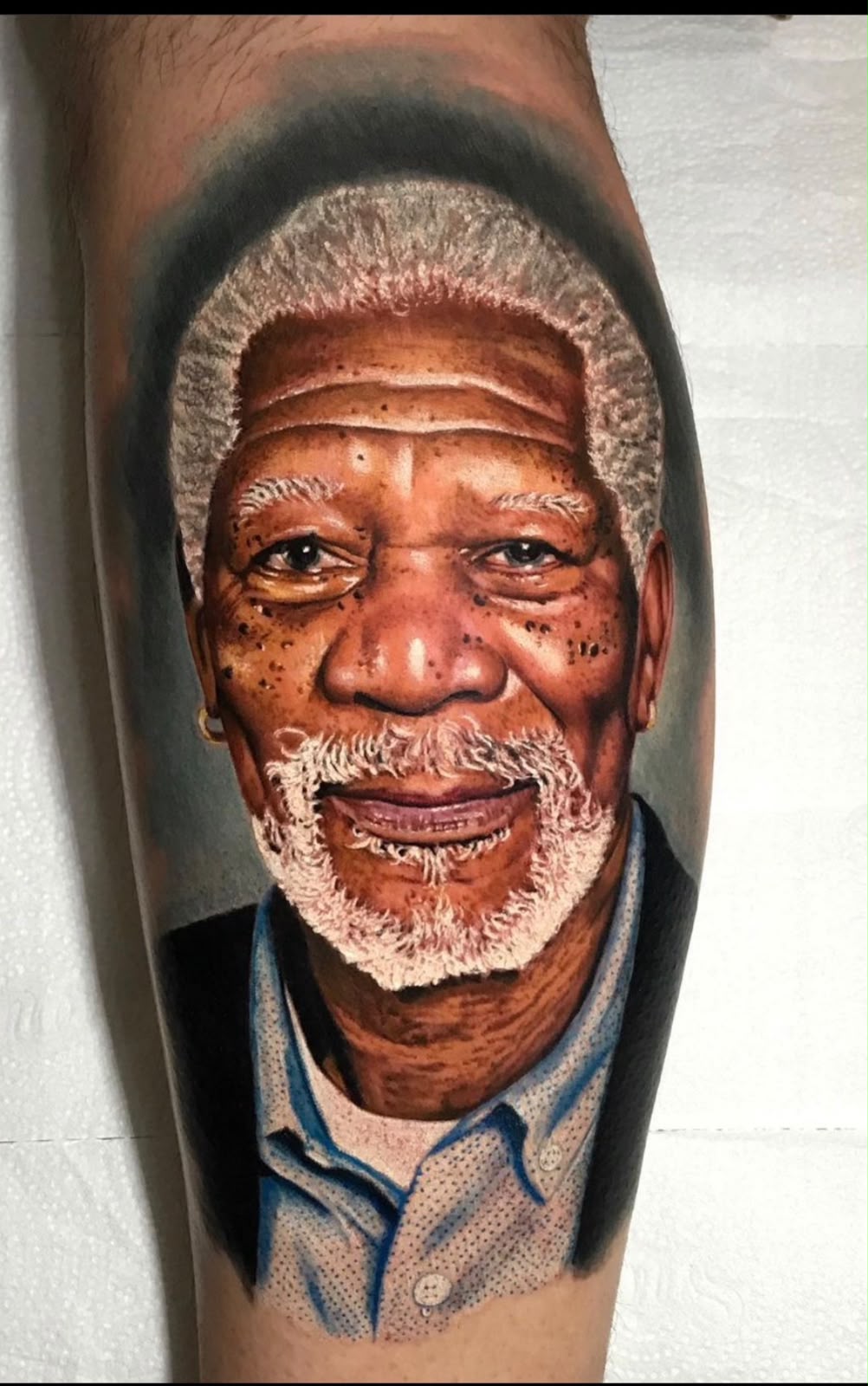 Tatuagem Realismo Colorido Morgan Freeman na região panturrilha feita por Bagé em Porto Alegre
