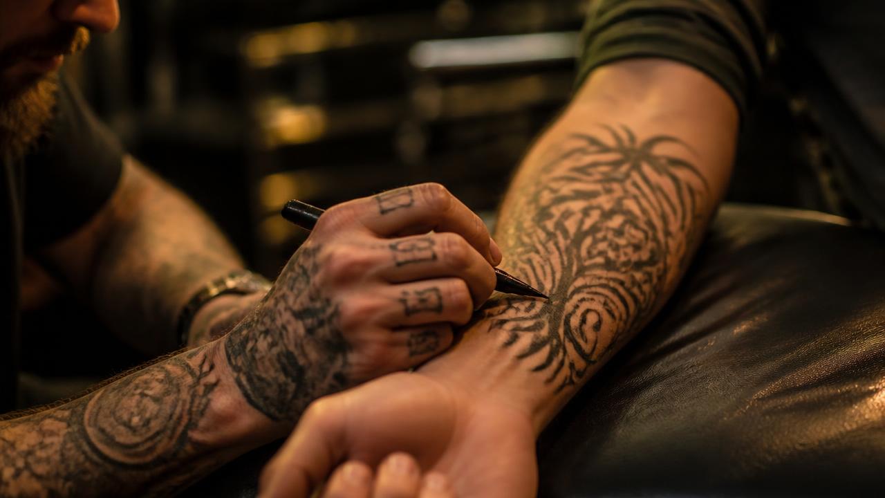 Tatuagem antiga sendo coberta por um novo desenho em preto e cinza no antebraço