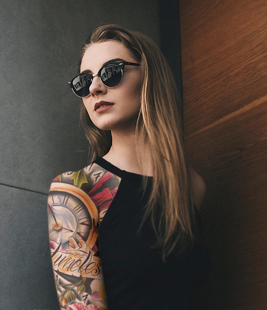 Mulher com braço fechado em tatuagens, posando com segurança