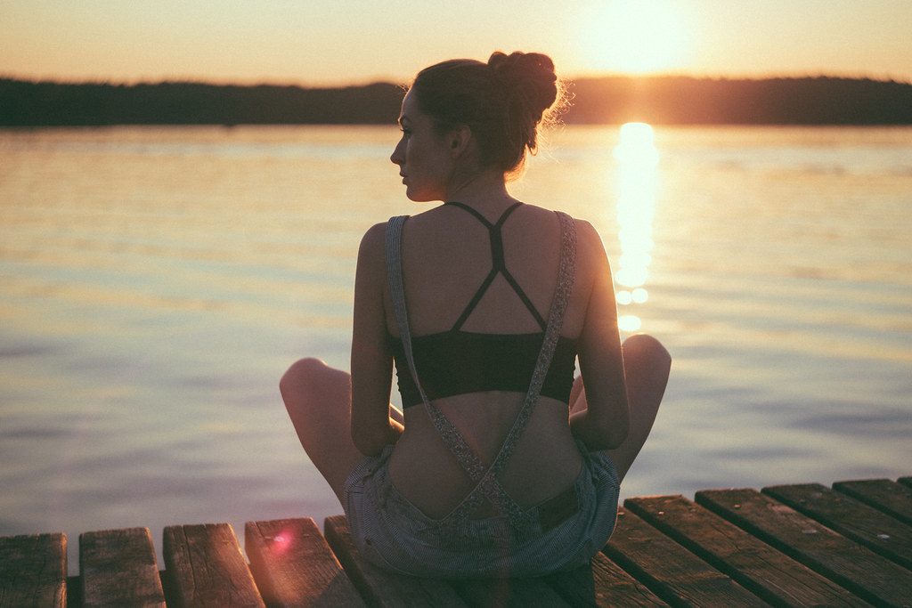 Silhueta de pessoa meditando ao pôr do sol, símbolo de saúde mental